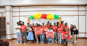 Group of Black youth dressed in read and holding posters for a youth program