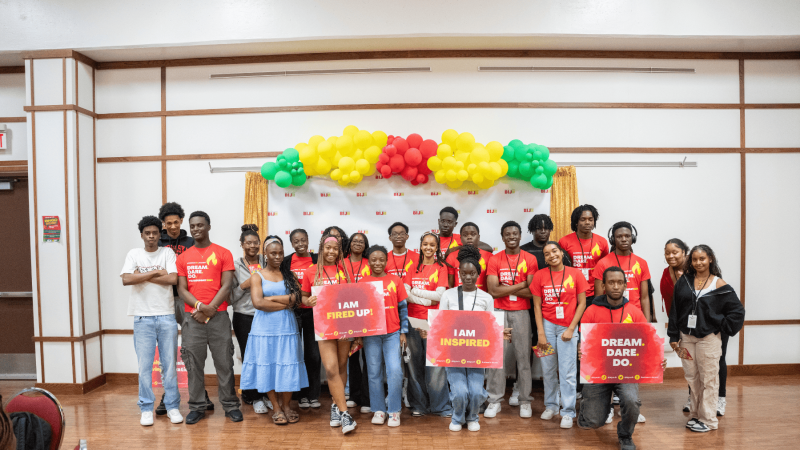 Group of Black youth dressed in read and holding posters for a youth program