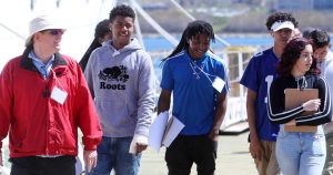 Group of youth wearing lanyards on a workplace tour lead by guide