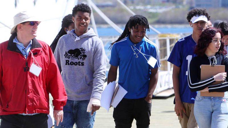Group of youth wearing lanyards on a workplace tour lead by guide